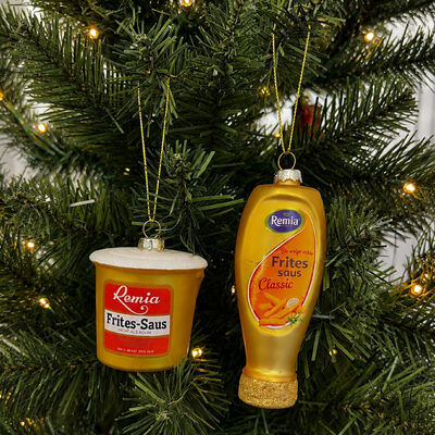 Twee glazen kerstornamenten van Remia in een kerstboom: een emmertje Frites-Saus en een fles Fritessaus Classic.