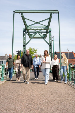 Het team van Florisgifts loopt op een zonnige dag richting de camera over een groene ophaalbrug.