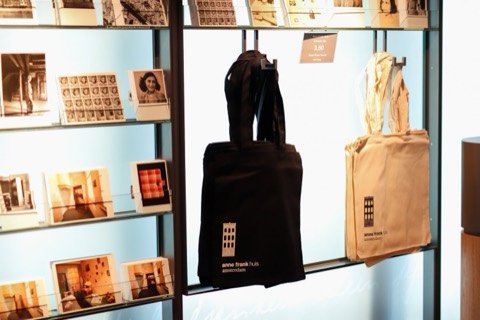 Zwarte en naturelkleurige katoenen tote bags met het logo van het Anne Frank Huis, in de museumwinkel.