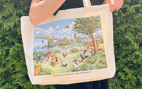 Een canvas shopper van Boekhandel Van Rietschoten met een full colour illustratie van Rotterdam, vastgehouden voor een groene haag.