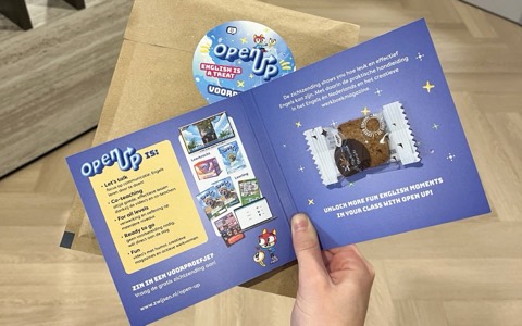 Een geopend brievenbusgeschenk van Uitgeverij Zwijsen voor de methode Open Up, met kaart en verpakte koek.