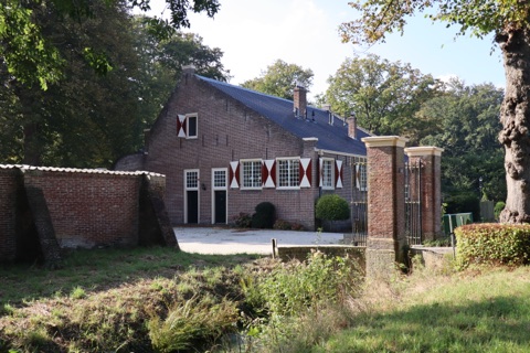 Het monumentale pand van Greenmotion met rood-witte luiken, gezien vanaf de weg naast het toegangshek.