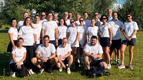 Groepsfoto van het team van Kick and Rush in witte T-shirts, staand en geknield op een grasveld.