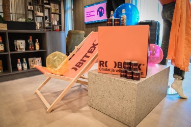 De Robitex-showroom met een gebrandde strandstoel en een kist relatiegeschenken met de tekst 'Omdat je wilt uitpakken'.