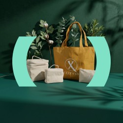 Een okergele shopper en drie linnen toilettassen van Extenso, gefotografeerd tussen groene takken.
