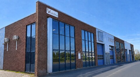 Het bedrijfspand van ViveleDon: een hoekgebouw van rode baksteen met hoge glazen puien en het ViveleDon-logo op de gevel.