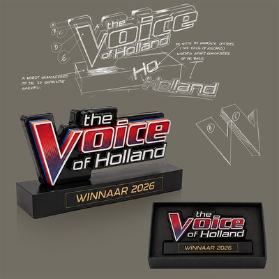 De winnaarsaward van The Voice of Holland naast de ontwerpschetsen: het logo in reliëf op een zwarte sokkel met de tekst 'Winnaar 2026', en dezelfde award in zijn geschenkdoos.
