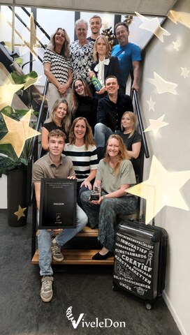 Het team van ViveleDon, samen op een trap gefotografeerd tussen kerstversiering van gouden sterren.