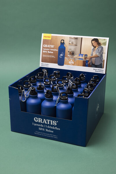 Een blauw display vol blauwe aluminium drinkflessen met karabijnhaak en SPA Reine-logo, met daarboven een actiekaart met de tekst 'GRATIS 1 gourde / 1 drinkfles'.