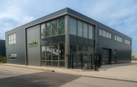 Het bedrijfspand van ZaaKado: een hoekgebouw met antracietgrijze gevelbeplating, hoge glazen puien en het ZaaKado-logo met pay-off op de zijgevel.